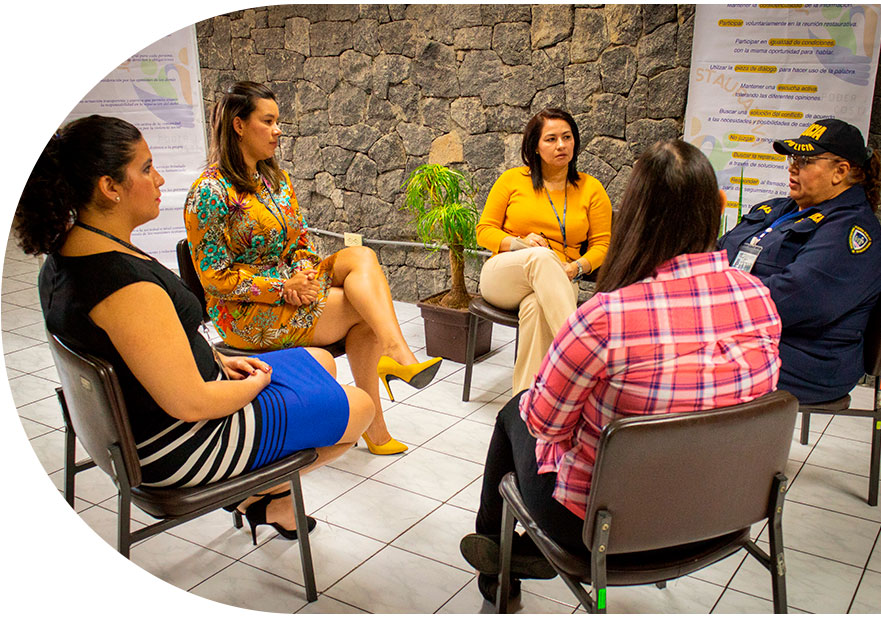 Cinco mujeres, sentadas, forman un circulo, ellas se muestran conversando