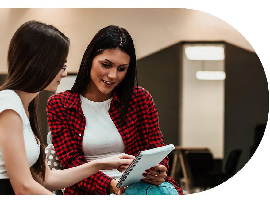 Dos mujeres revisan unos apuntes de una agenda, una ellas la sostiene en sus manos