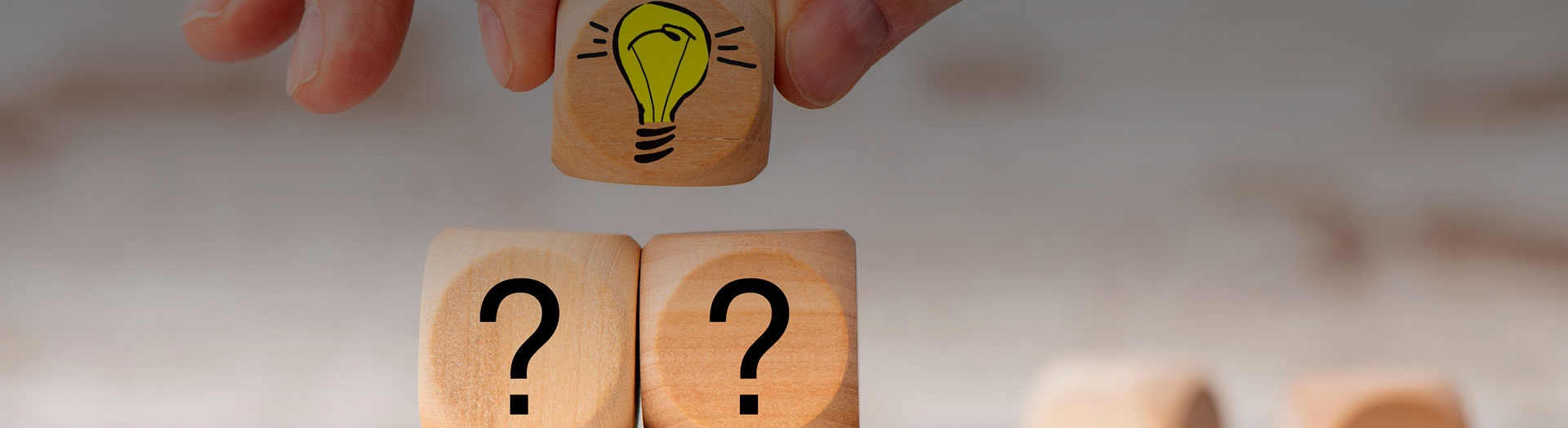 Se muestra una mano colocando un sexto cubo, pequeño, de madera, con un bombillo amarillo dibujado