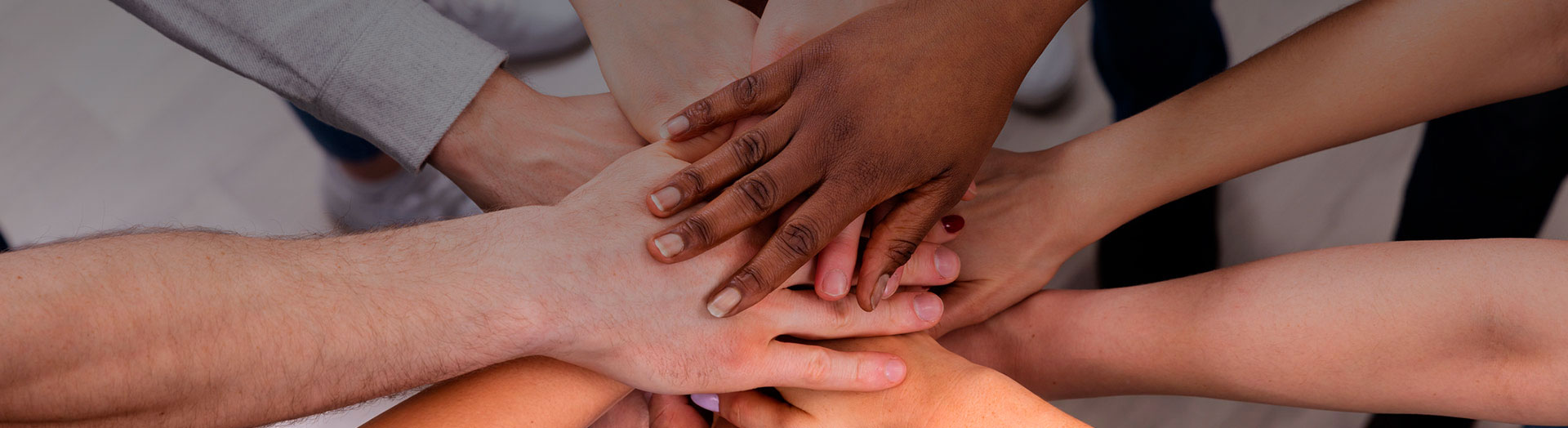 Grupo de personas forman circulo y colocan sus manos unas sobre otras