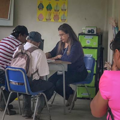Trabajadora social conversa con dos señores campesinos