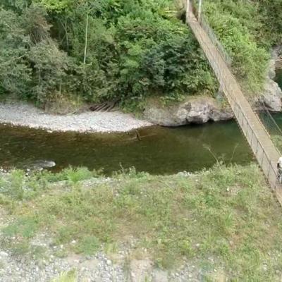 Tres personas cruzan un puente, abajo del puente se muestra el río