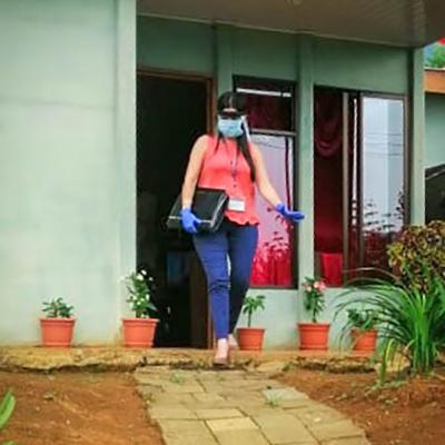 Mujer se muestra saliendo de una casa, con documentos en sus manos